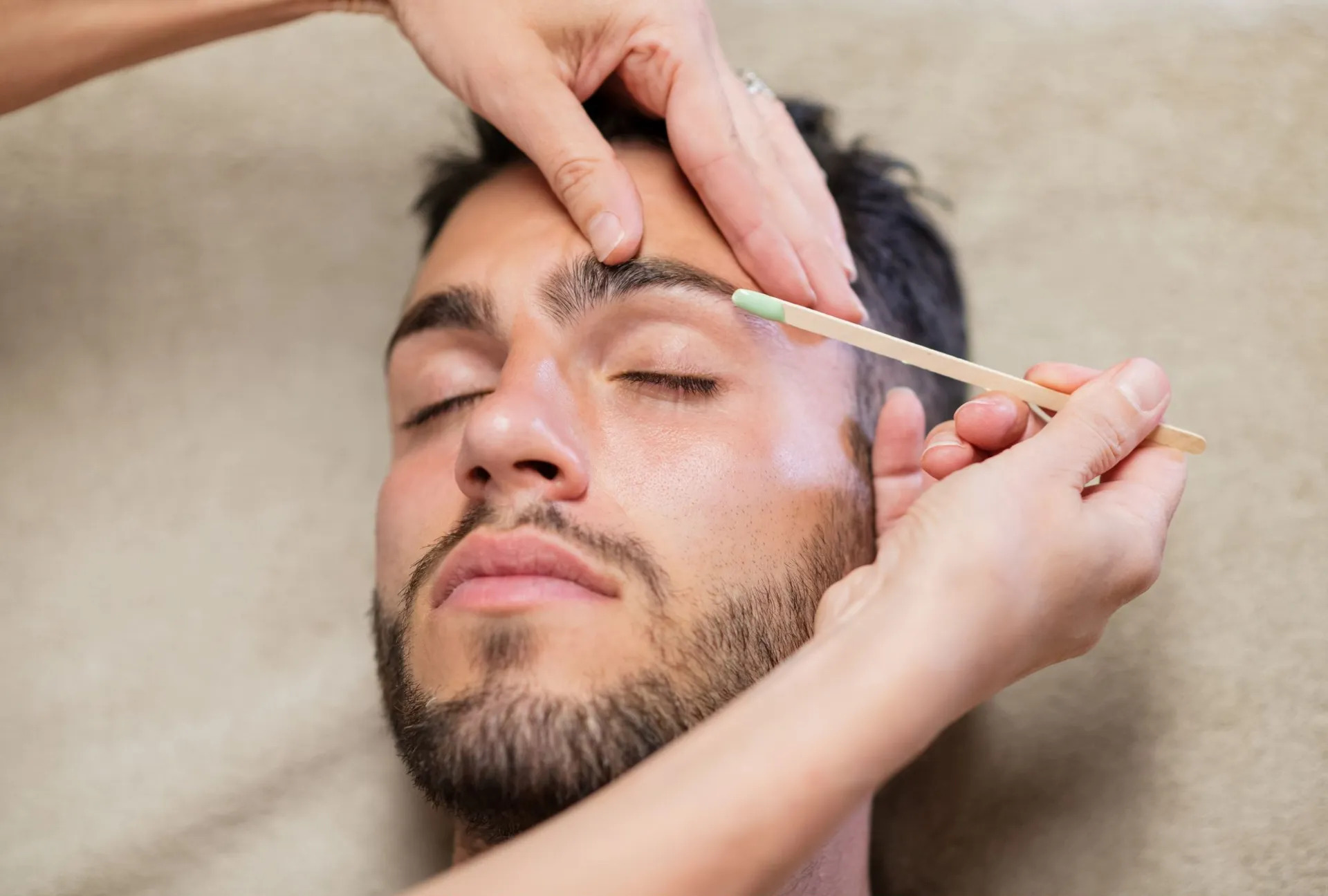 Technician shaping a client's eyebrows during a facial wax